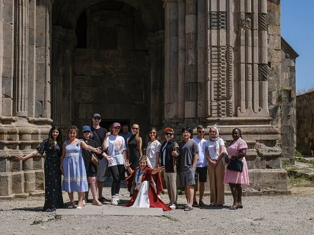 Group of tourists posing with a woman in traditional Armenian dress.