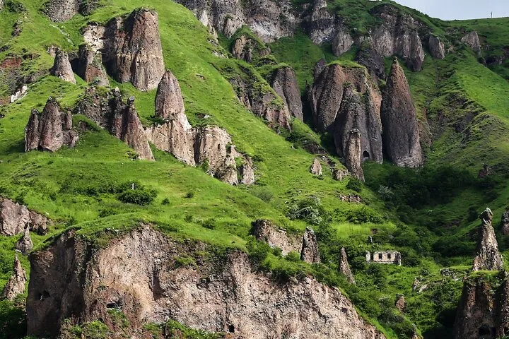 Steep rocky mountain slopes with unique pillar-like rock formations and caves.