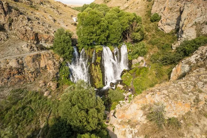 Aerial view of Shaki Waterfall cascading down rocks surrounded by trees.